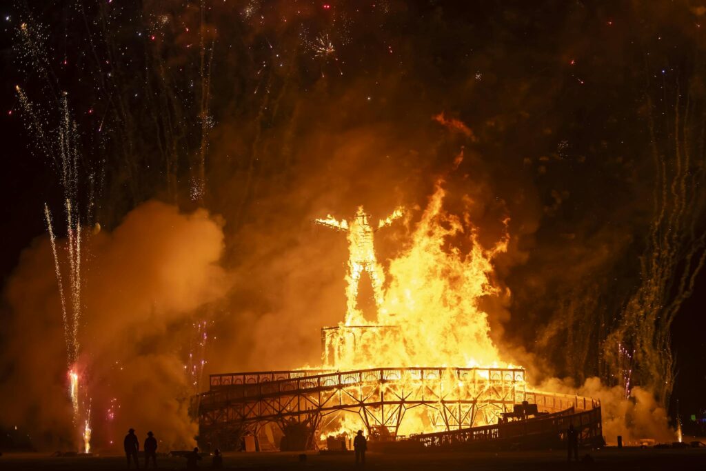 A vibrant display of fire and fireworks at the iconic Burning Man Festival, captured during a night event.